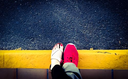 Low section of woman standing yellow line