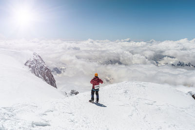 Woman standing on snow covered mountain against sky