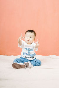 Portrait of cute baby boy playing with toy on bed at home