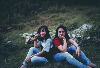 Portrait of happy young woman sitting on land