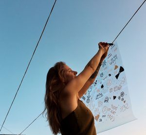 Low angle view of woman standing against clear sky