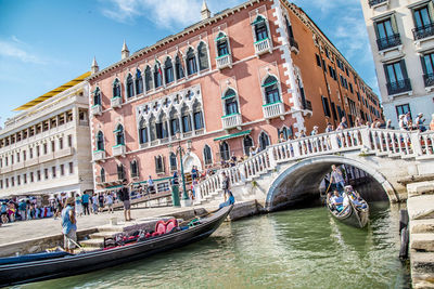 People on boat in canal along buildings