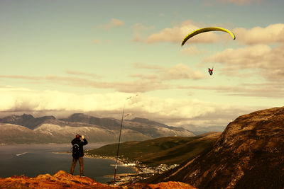 Rear view of man standing on mountain against sky