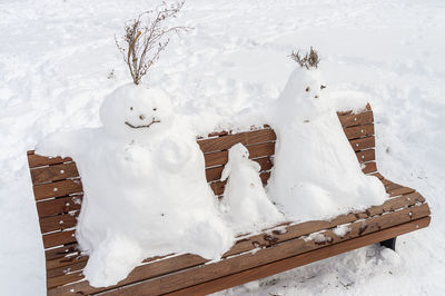 High angle view of snowmen on bench