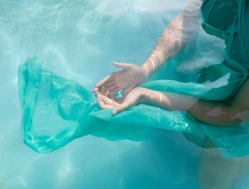 Midsection of woman holding pyramid crystal in swimming pool