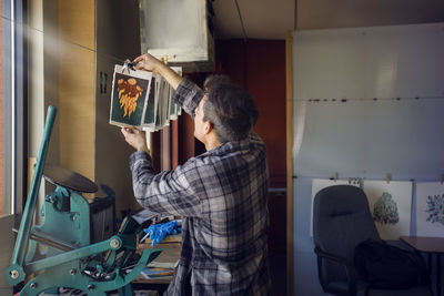 Male lithograph worker hanging prints to dry at workshop