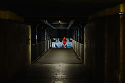 Rear view of woman walking in illuminated underground walkway