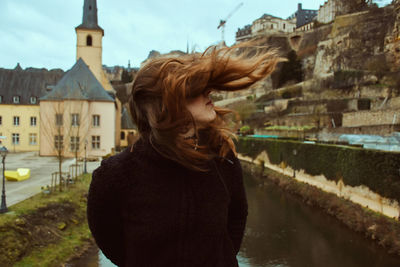 Woman standing by canal against buildings in city