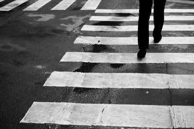 Low section of man walking on zebra crossing