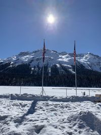 Scenic view of snow covered mountains against bright sun