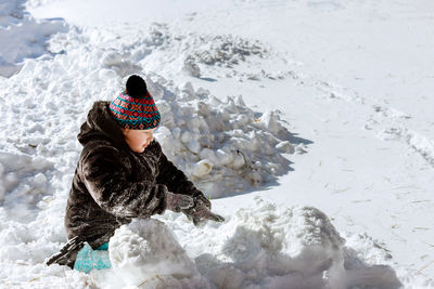Girl wearing knit hat playing on snow outdoors