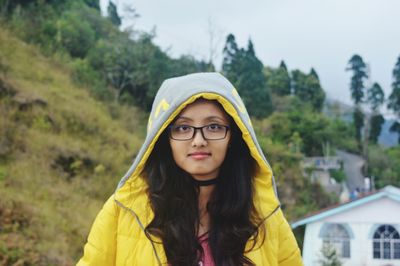 Portrait of young woman wearing warm clothing while standing against trees