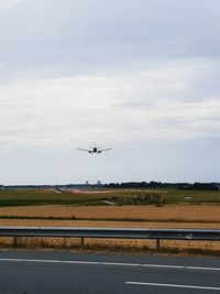 Airplane flying over runway against sky