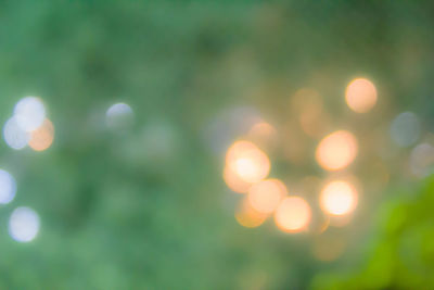 Defocused image of illuminated lights against sky