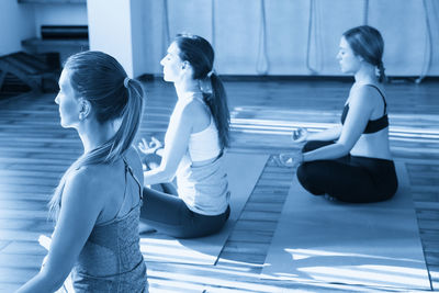 Side view of young woman sitting on floor