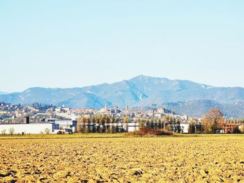 Scenic view of field by buildings against clear sky