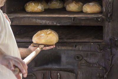 Man putting loaf of bread in oven at bakery