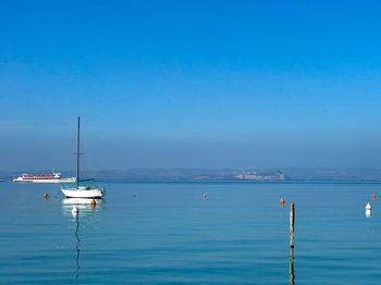 Sailboats in sea against blue sky