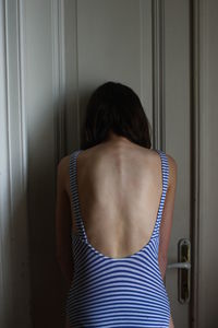 Rear view of woman standing against door at home