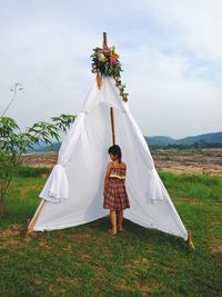 Woman with umbrella standing on field against sky