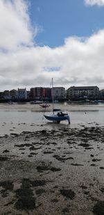 Boats moored on beach against sky in city