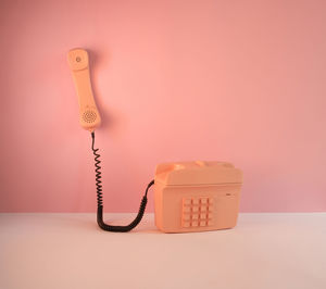 Close-up of telephone booth against pink background