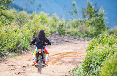 Woman riding her dirt-bike on forest track in pak chong / thailand