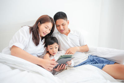 Family watching video over digital tablet while relaxing on bed at home