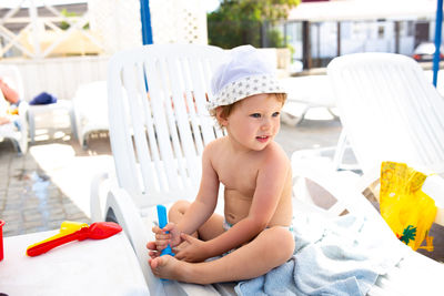 Small child in panama hat plays in the summer on sunny day near swimming pool