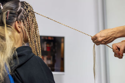 A stylist mother getting her teenage daughter senegalese braids in her home. 