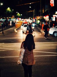 Rear view of women walking on road at night