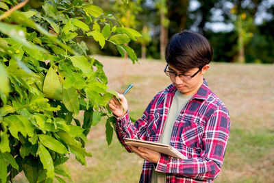 Full length of young woman holding plant