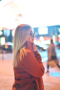 Midsection of woman wearing sunglasses standing in city