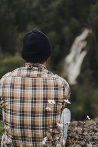 Rear view of man sitting on rock