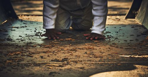 Midsection of boy crawling on footpath