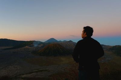 Silhouette man looking at mountains against sky during sunset