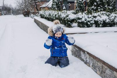 Best outdoor winter activities for kids. cute kid boy in blue winter jacket playing snowballs on