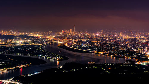 High angle view of illuminated bridge and buildings in city at night