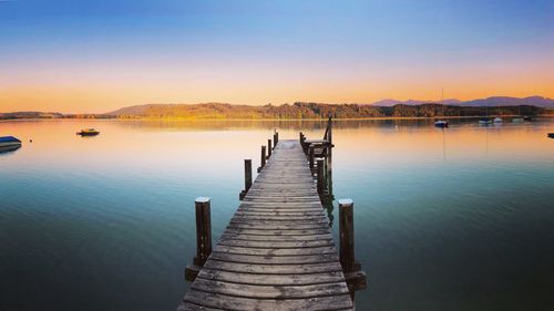 Pier over lake against sky during sunset