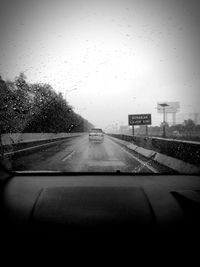 Cars on road seen through wet window in rainy season