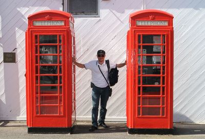 Full length of man standing amidst telephone booths in city