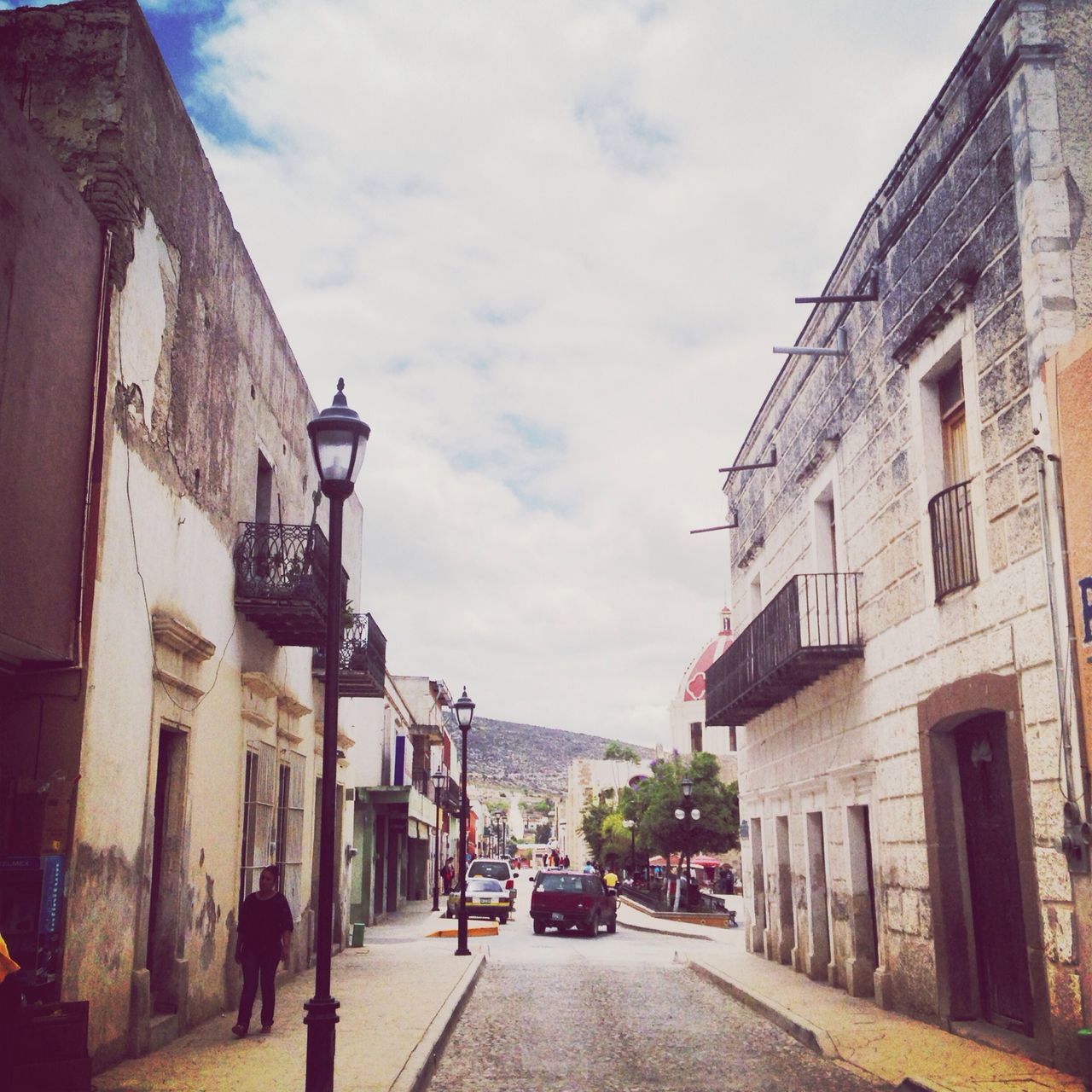 building exterior, architecture, built structure, street, the way forward, sky, city, road, transportation, diminishing perspective, car, residential building, building, residential structure, city life, vanishing point, walking, incidental people, city street