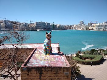 Man sitting by sea against clear sky