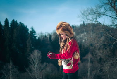 Smiling girl wearing fur hat while holding snow outdoors