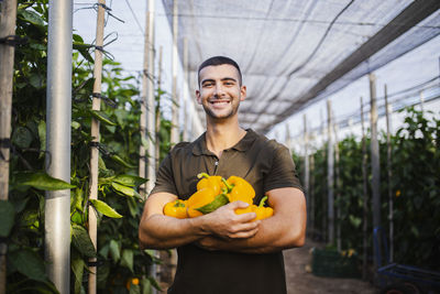 Portrait of smiling young man standing in greenhouse