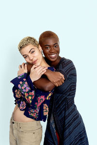 Portrait of smiling lesbian couple embracing against white background