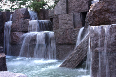 Water splashing on rocks against waterfall