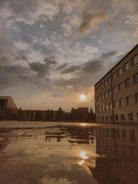 Reflection of buildings in puddle at sunset