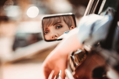 Portrait of woman reflecting on side-view mirror