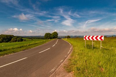 Road amidst field against sky